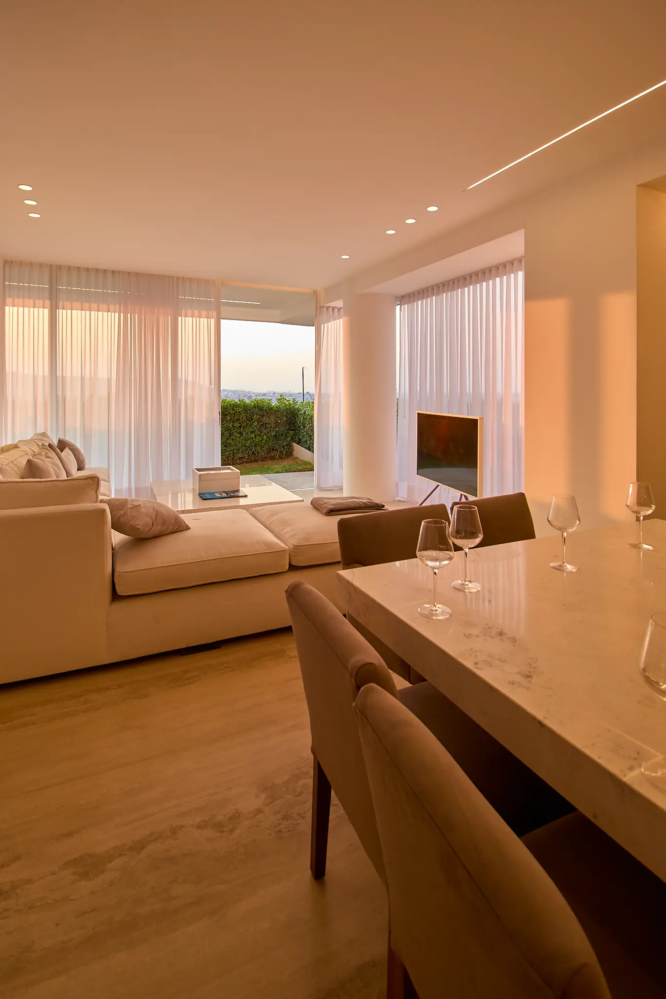 Estancia y comedor de Vedana con la luz del atardecer filtrada por las cortinas