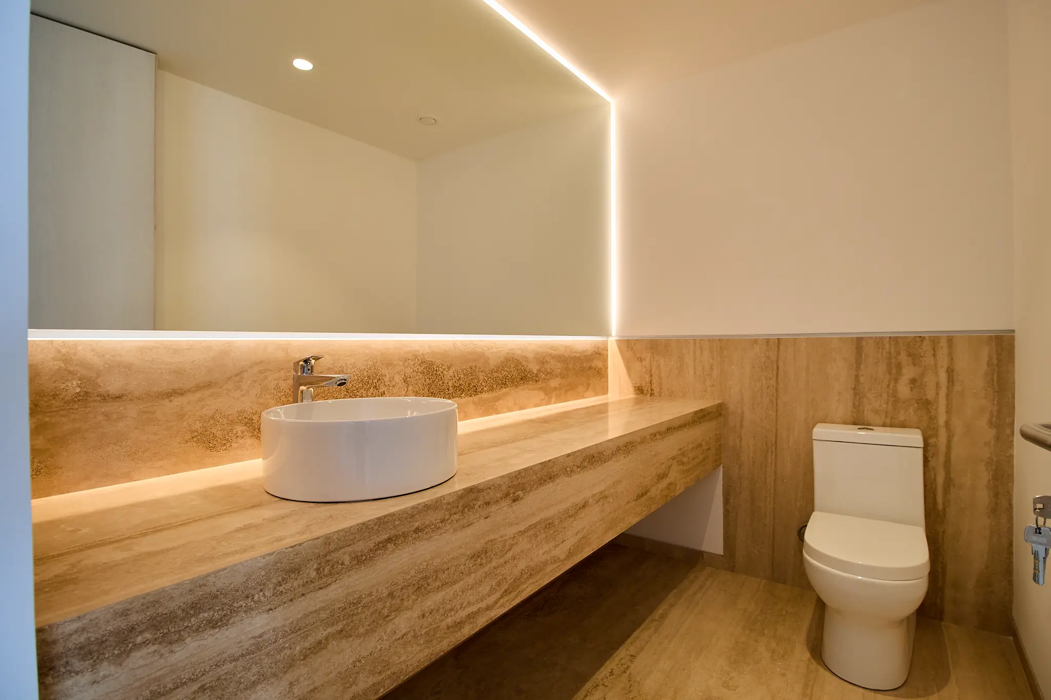 Baño en travertino con luz indirecta